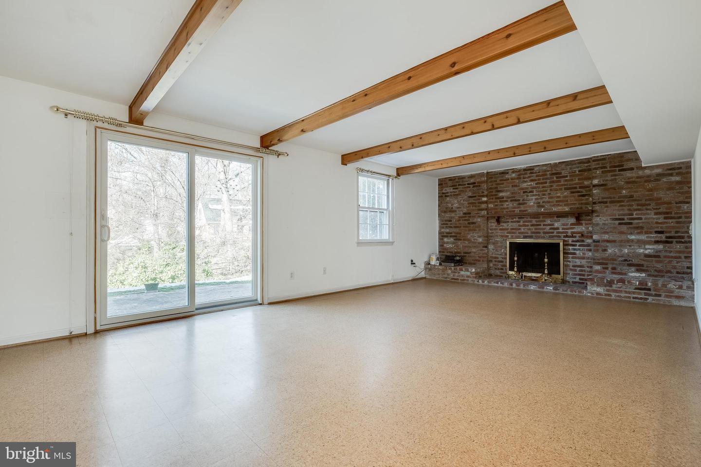 Living room with exposed wood beams and brick fireplace at the inherited Chapel Square home in Annandale, Virginia - sold by David Mount in 2022 as an as-is listing with multiple competing offers.