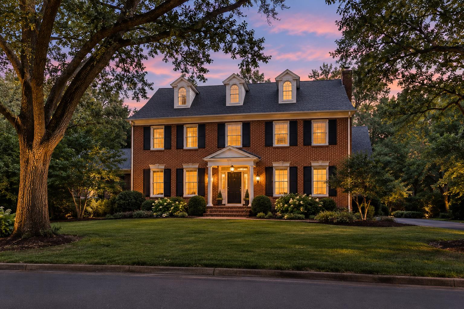 Red brick Colonial single-family home in Northern Virginia at twilight with warm interior lights on a tree-lined street, no visible address